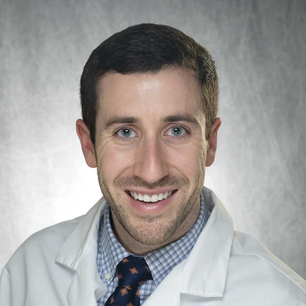 Dr. O'Bryan, a dark-haired man in a checkered shirt, blue tie, and white coat.