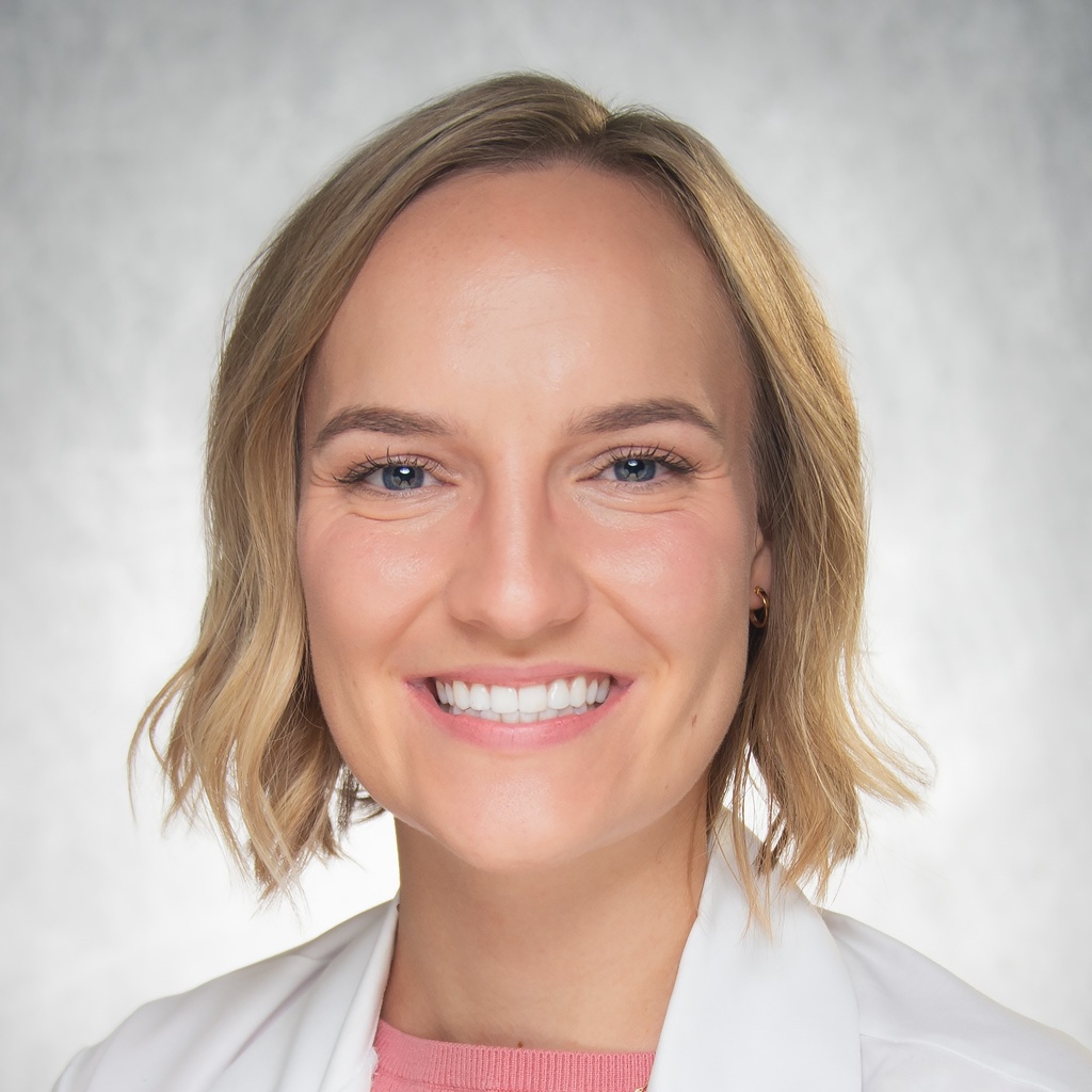 Dr. Anderson, a smiling blonde woman wearing a pink shirt and white coat.