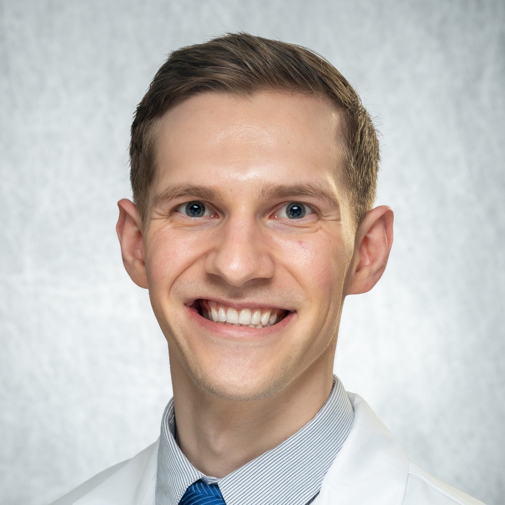 Dr. Blad, a blond man wearing a blue tie and white coat.
