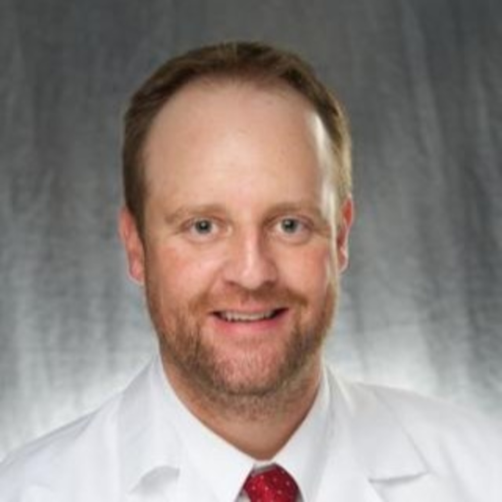 Michael Elliott, a man wearing a red tie and white coat.