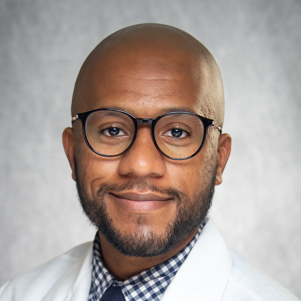 Dr. Sharif-Sidi, a man in glasses wearing a checkered shirt and white coat.