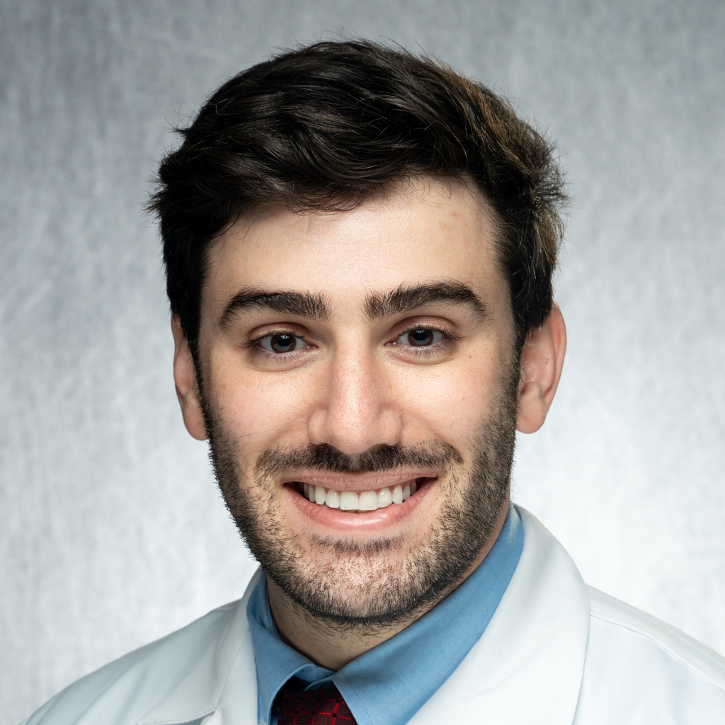 Dr. Palladino, a dark-haired man wearing a blue shirt, red tie, and white coat