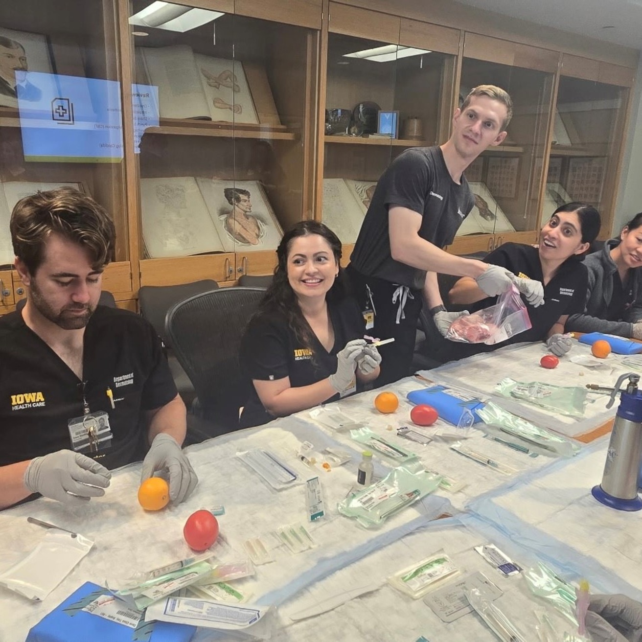 Five dermatology residents practice sutures on oranges.