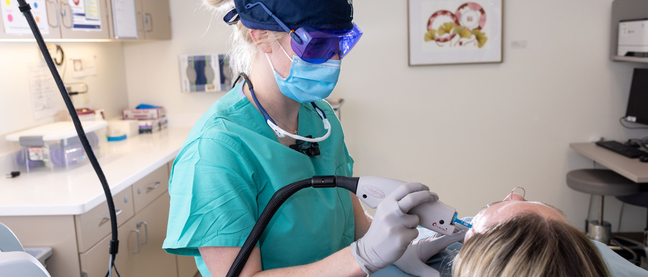 Dr. Jansen wears protective glasses and a mask as she uses a laser to treat a patient's face.